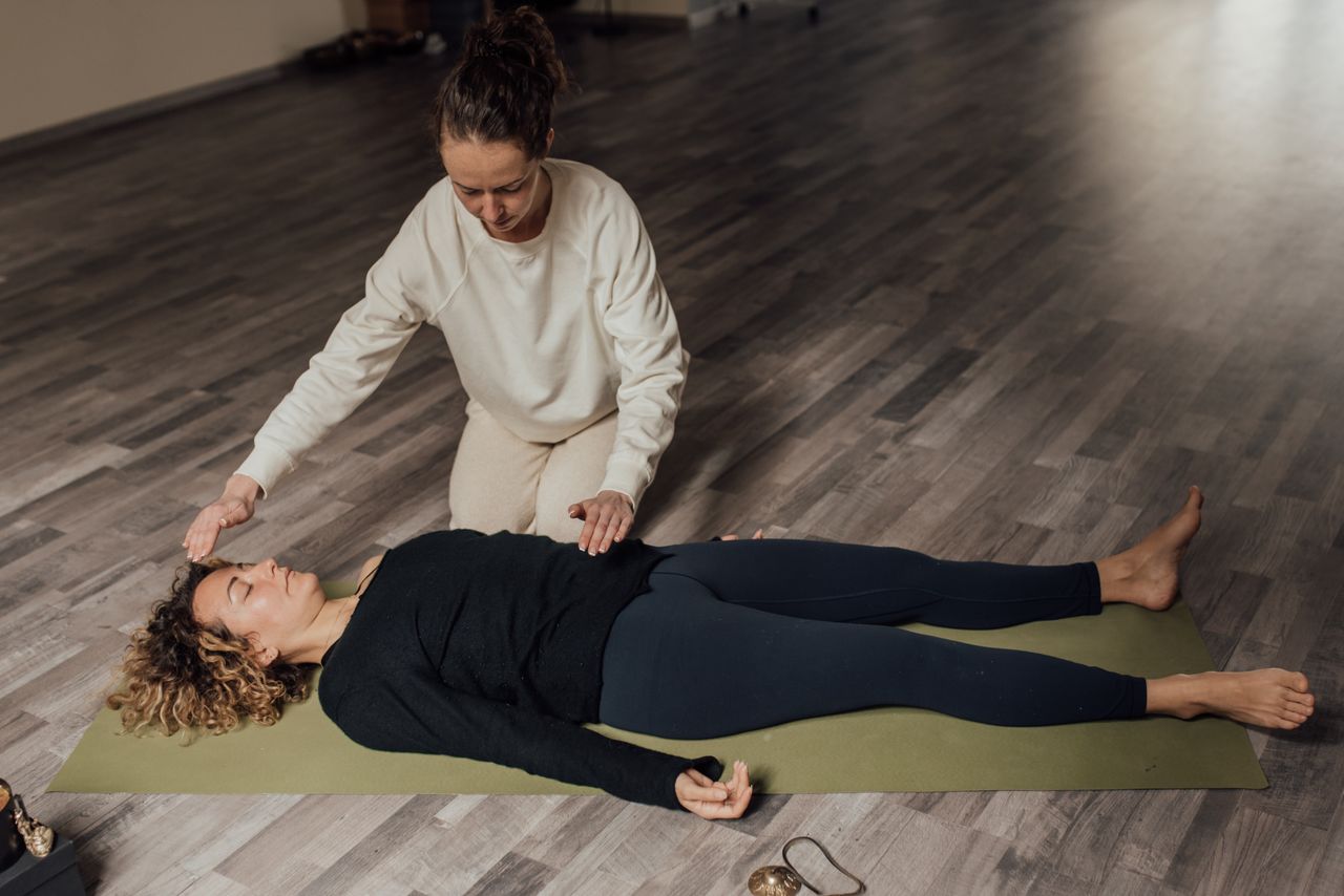 our-story Energy therapist healing barefoot female with closed eyes during meditation practice on floor in sunlight